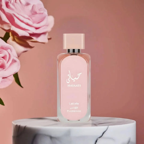 Lattafa Hayaati Florence Eau De Parfum spray in a 100ml bottle, shown with a velvet pouch, featuring elegant perfume packaging.