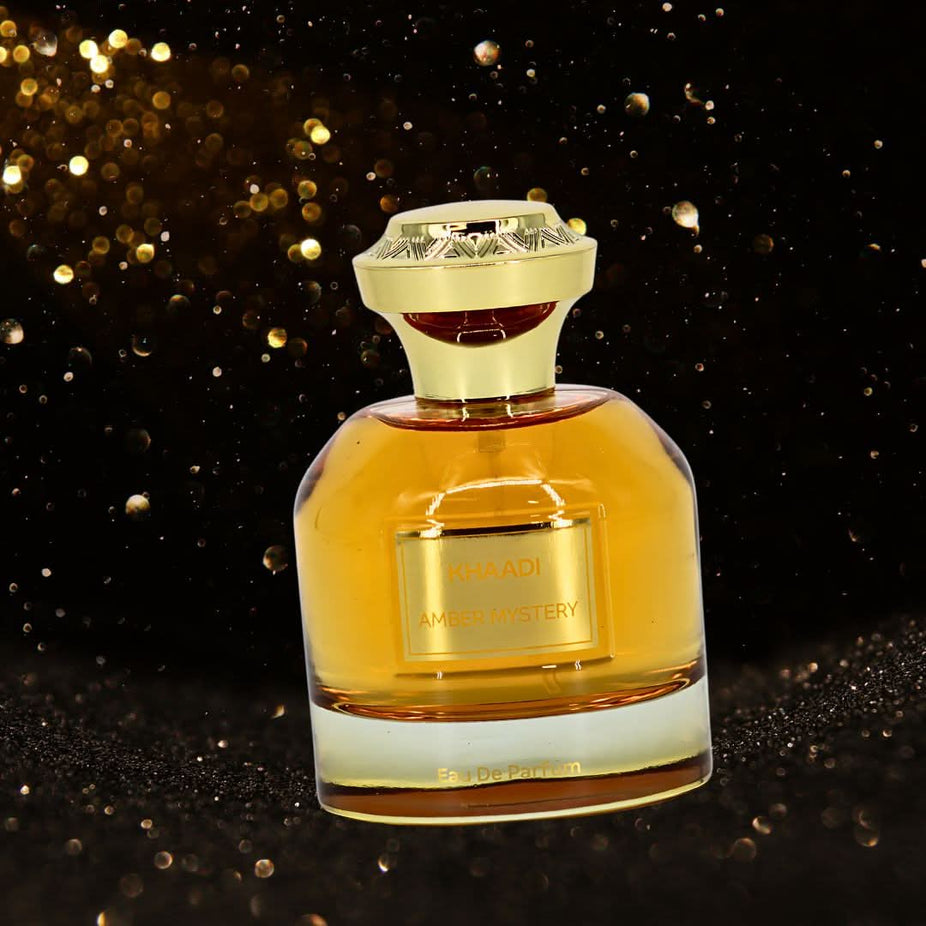Khaadi Amber Mystery Eau de Parfum spray in a velvet pouch, showcasing the 100ml bottle with amber-colored liquid and elegant packaging.