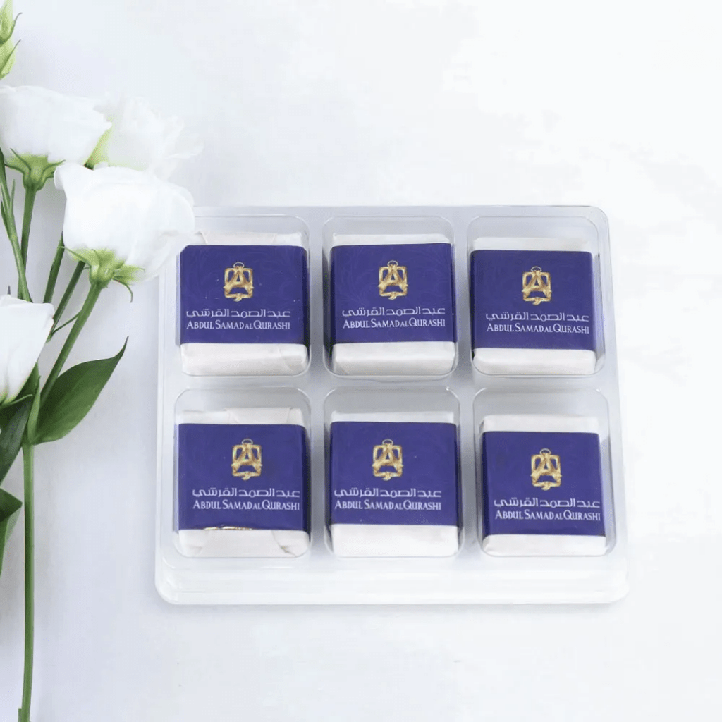 Six white solid musk cubes from Abdul Samad Al Qurashi, natural musk scent, in a clear container with a minimalist design.