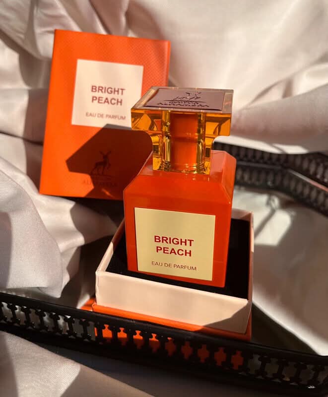 Bright Peach Eau de Parfum spray in 80ml Maison Alhambra velvet pouch, with a sleek glass bottle and soft pouch.